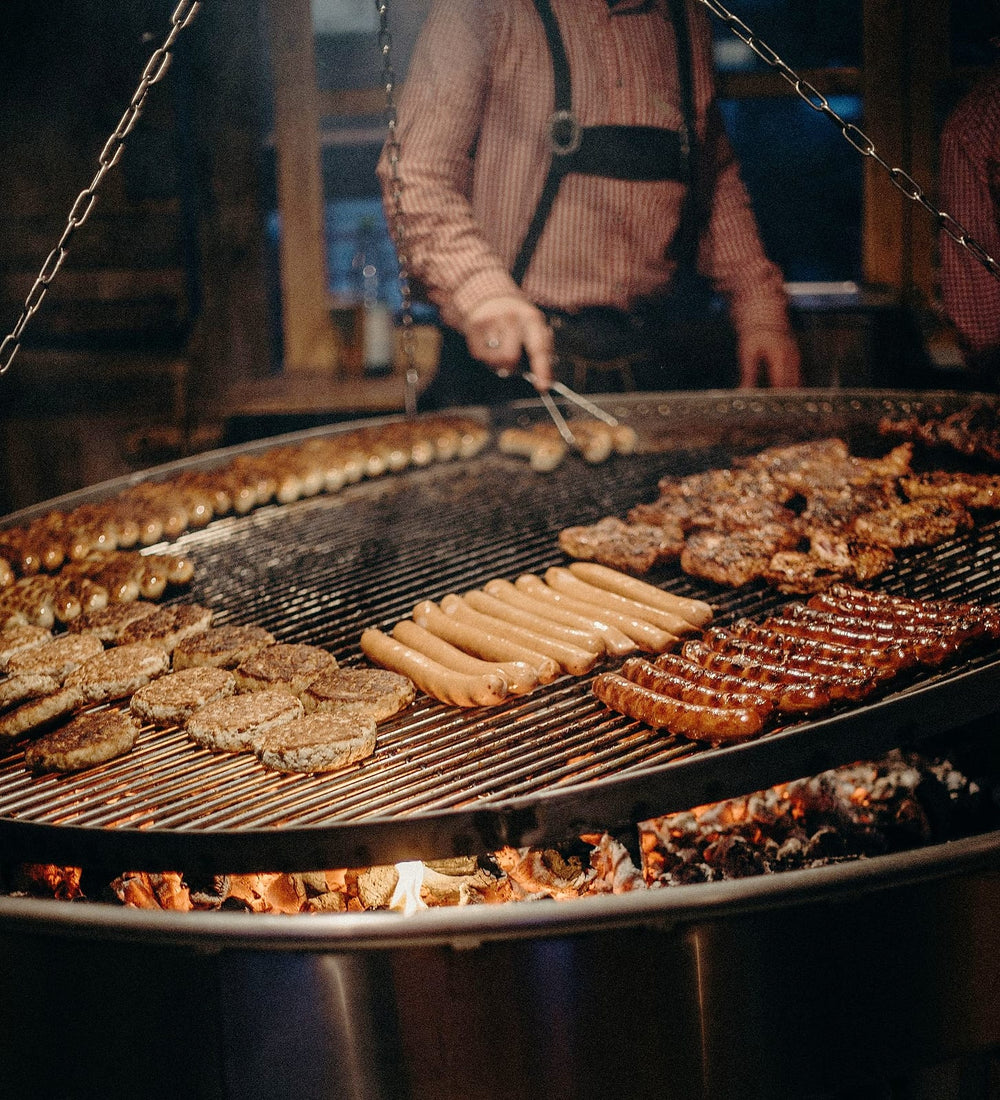 Large round grill full of burgers, sausages and steaks