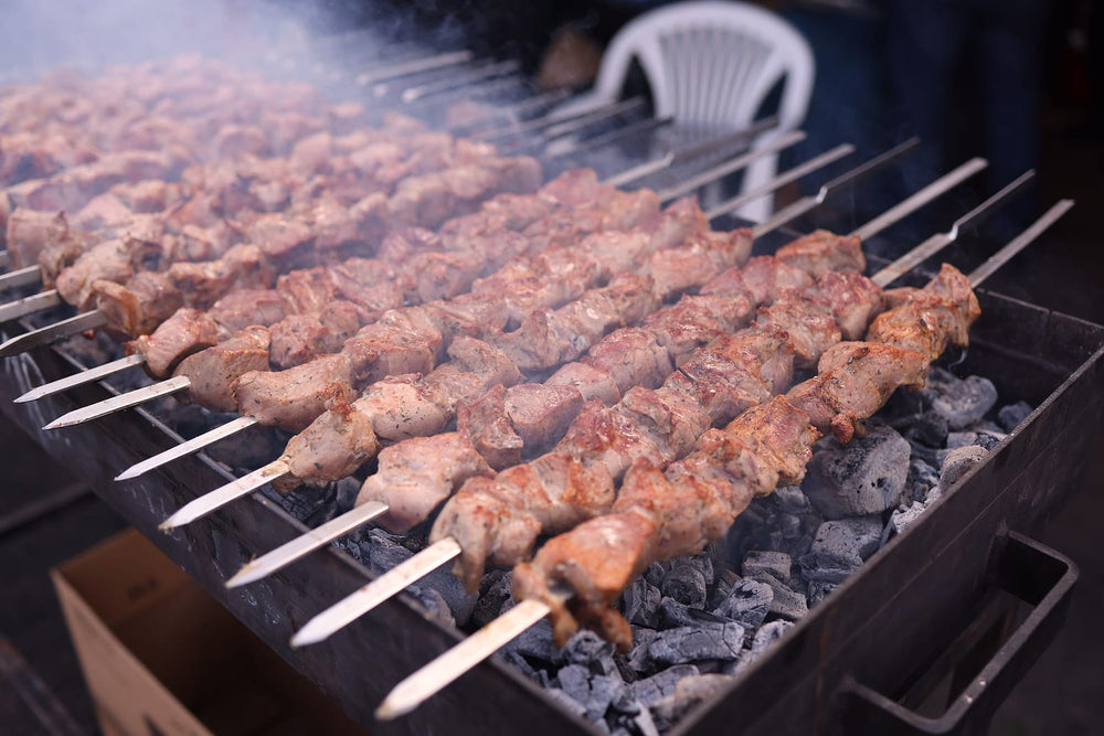 Rows of meat skewers over glowing charcoal