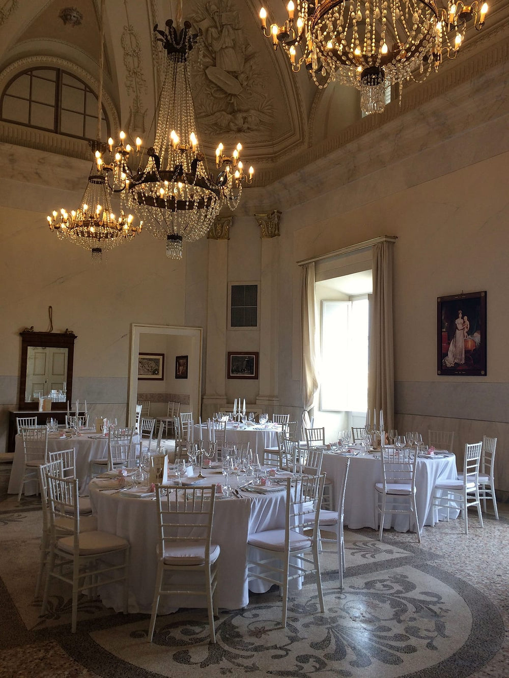 Feestzaal met gedekte ronde tafels en kroonluchters